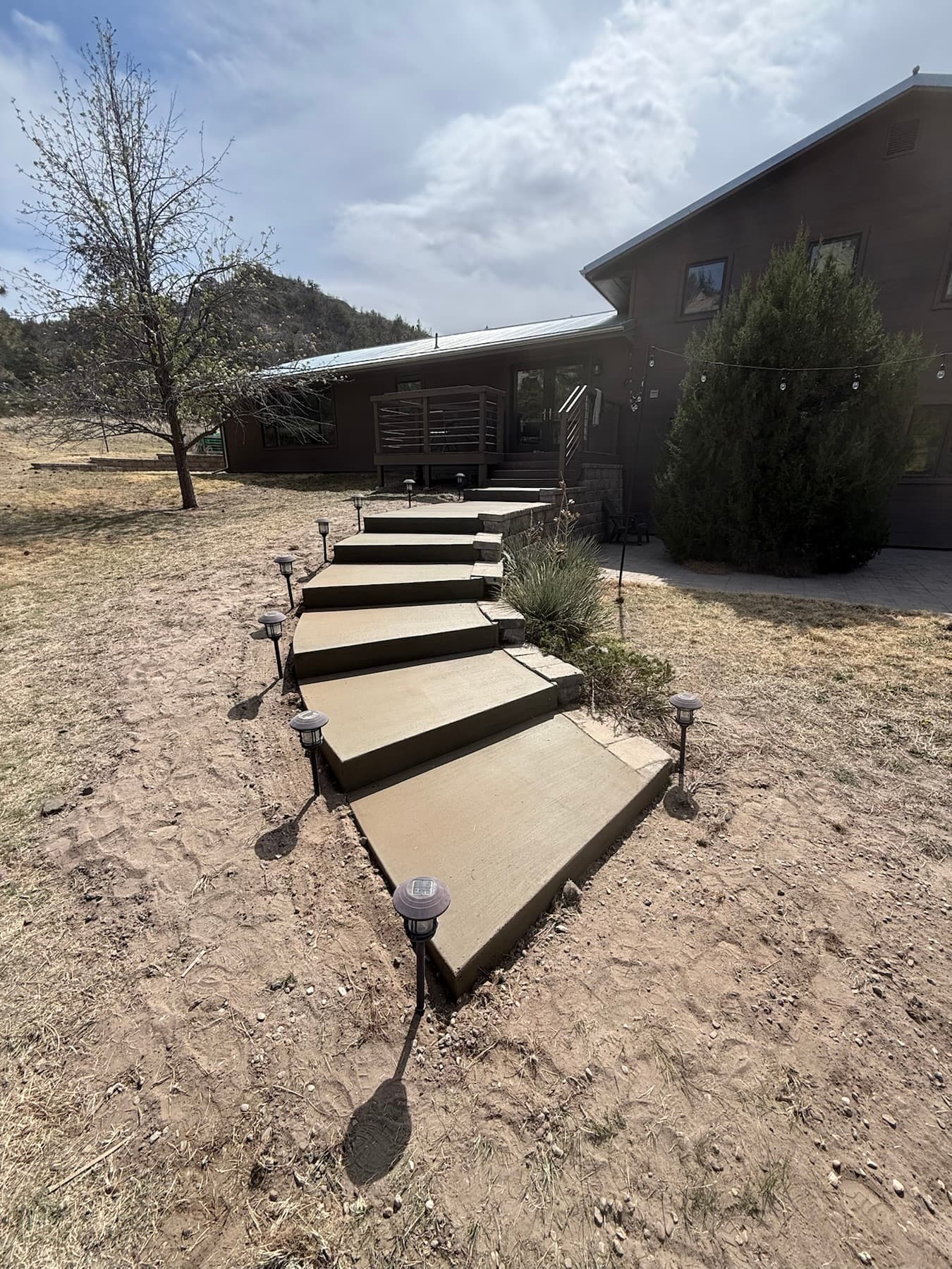 Curved concrete steps climbing a hillside to a home, poured by Gali Masonry